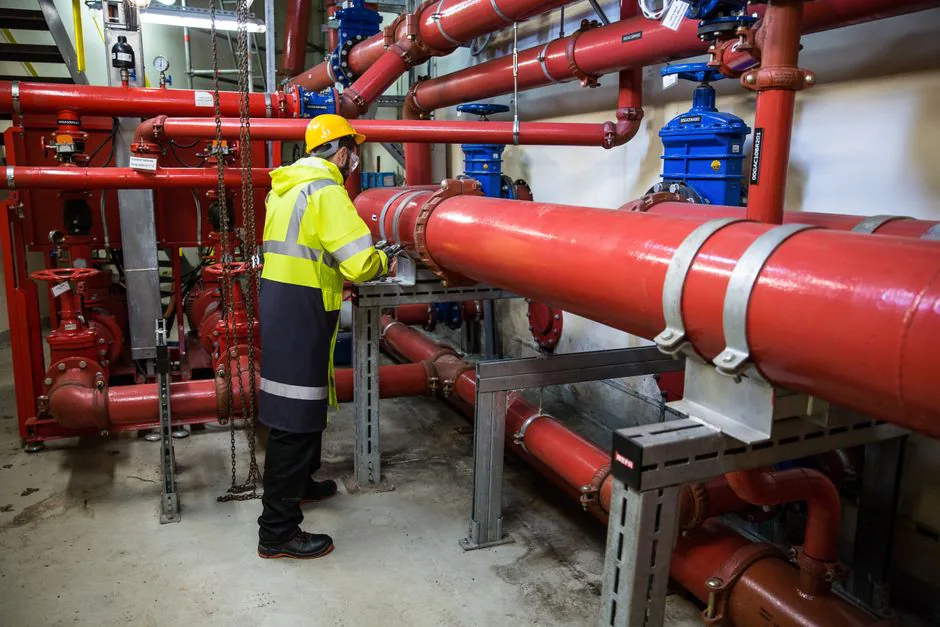 Técnico revisando tuberías y válvulas de una instalación de protección contra incendios