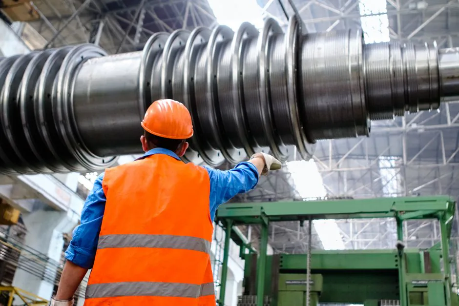 Profesional con casco y chaleco inspeccionando maquinaria en una instalación industrial