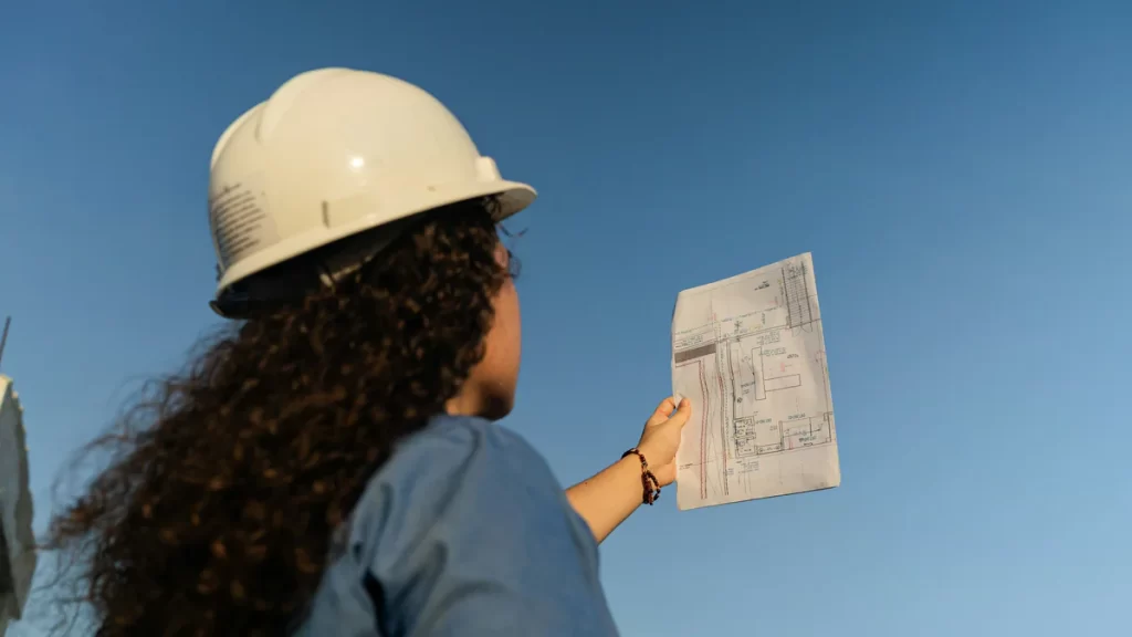Profesional con casco revisando un plano en una obra