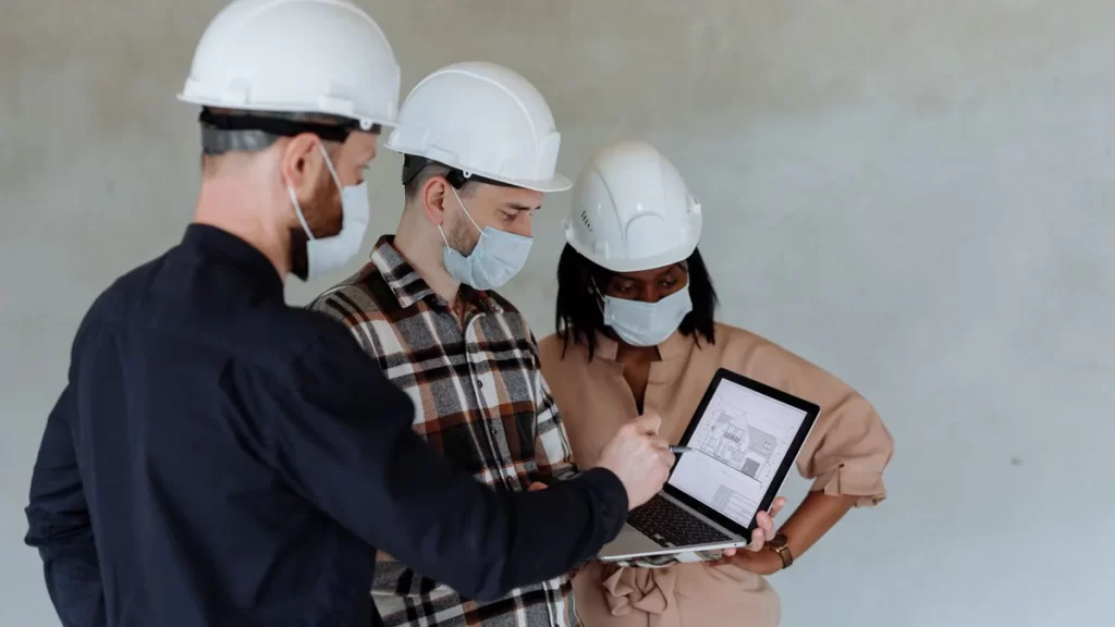 Equipo técnico de construcción revisando un plano digital en un portátil