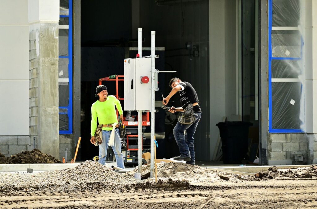 Dos operarios instalando un cuadro eléctrico en una obra